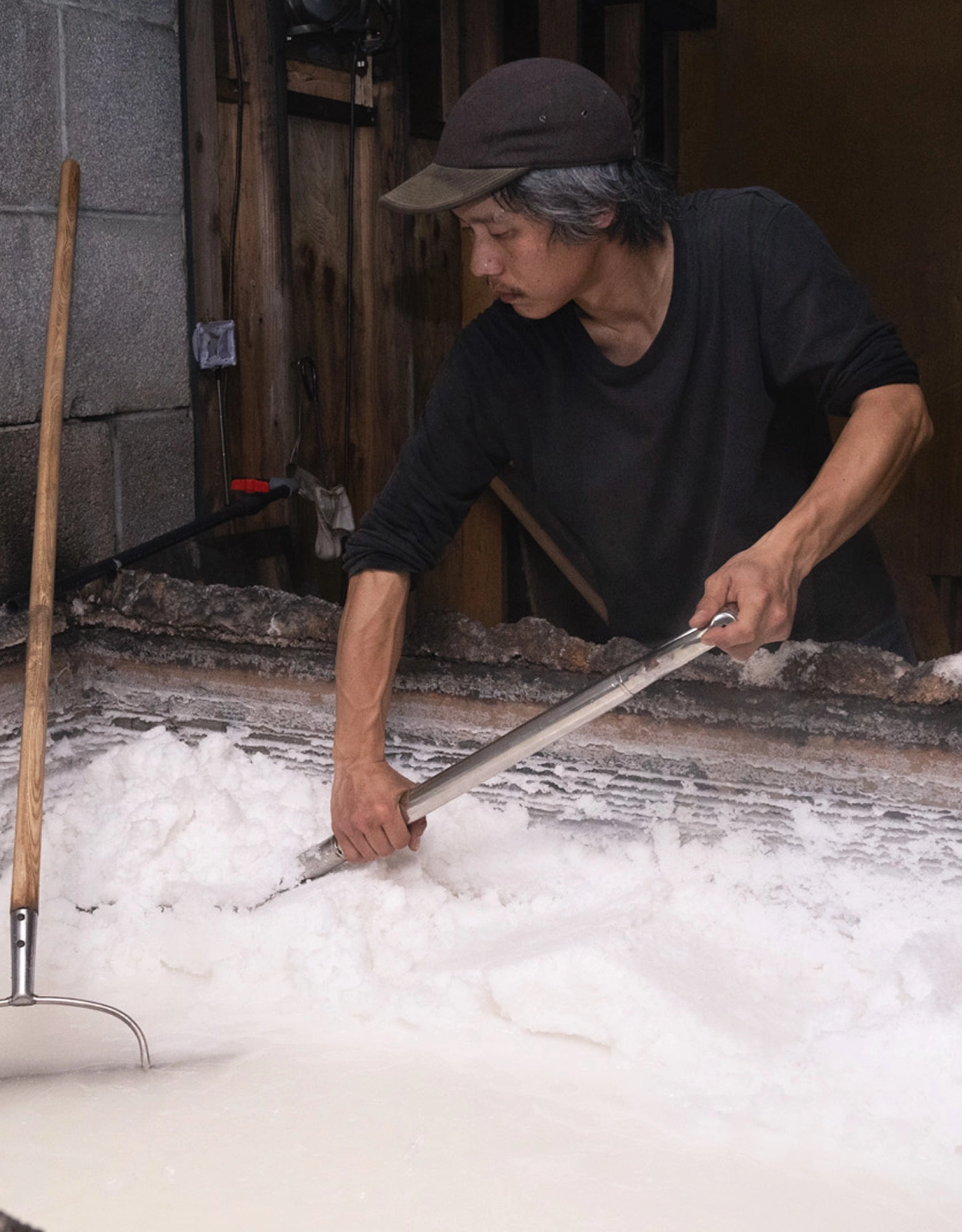 塩職人が結晶化した塩を平窯から樽へ移している